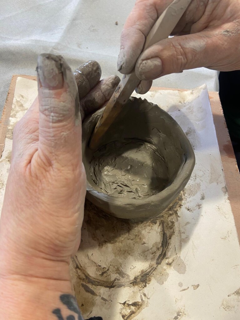 a close up of someone sculpting a clay pot