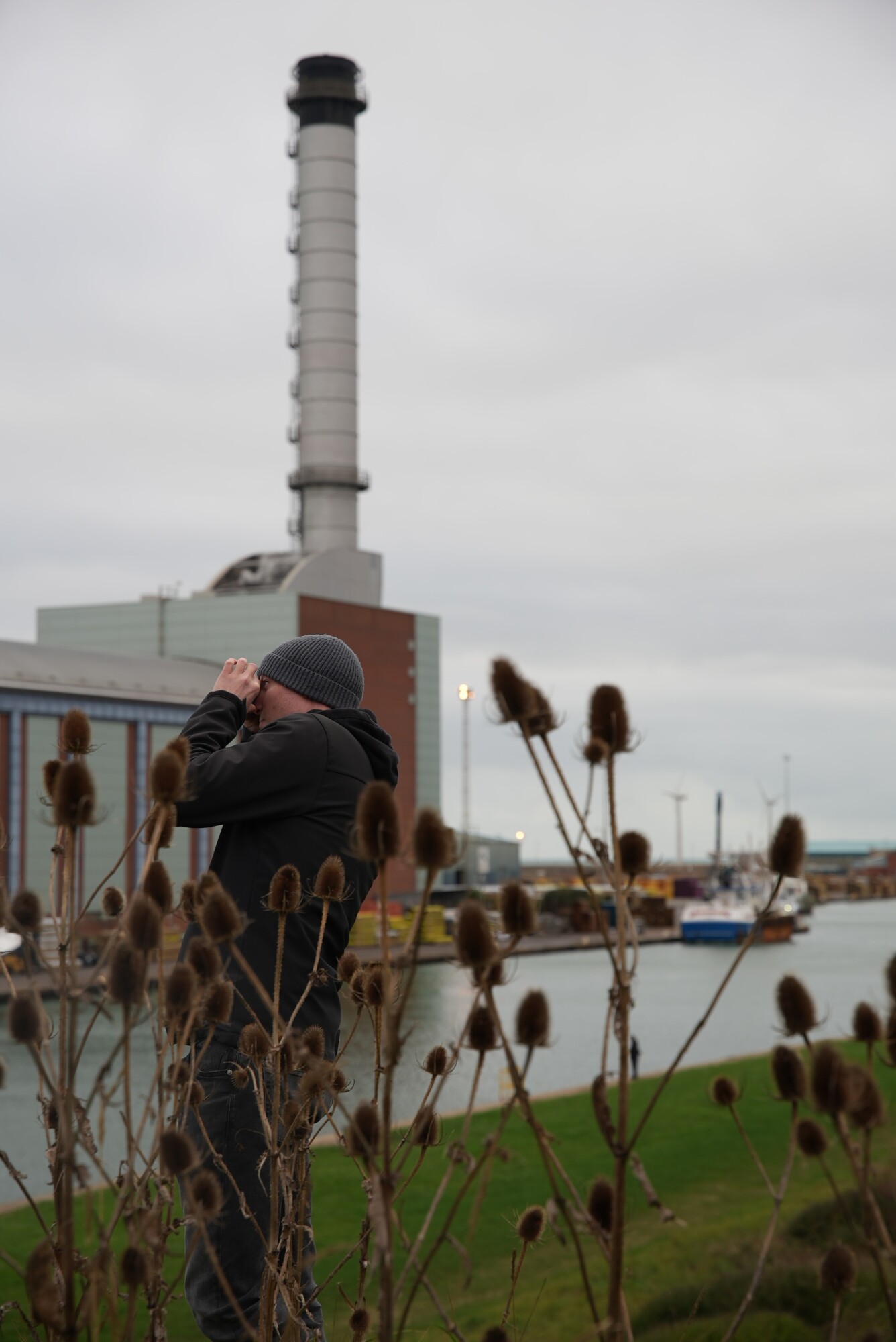 a person is taking a photograph, in the background is Shoreham Port and power station