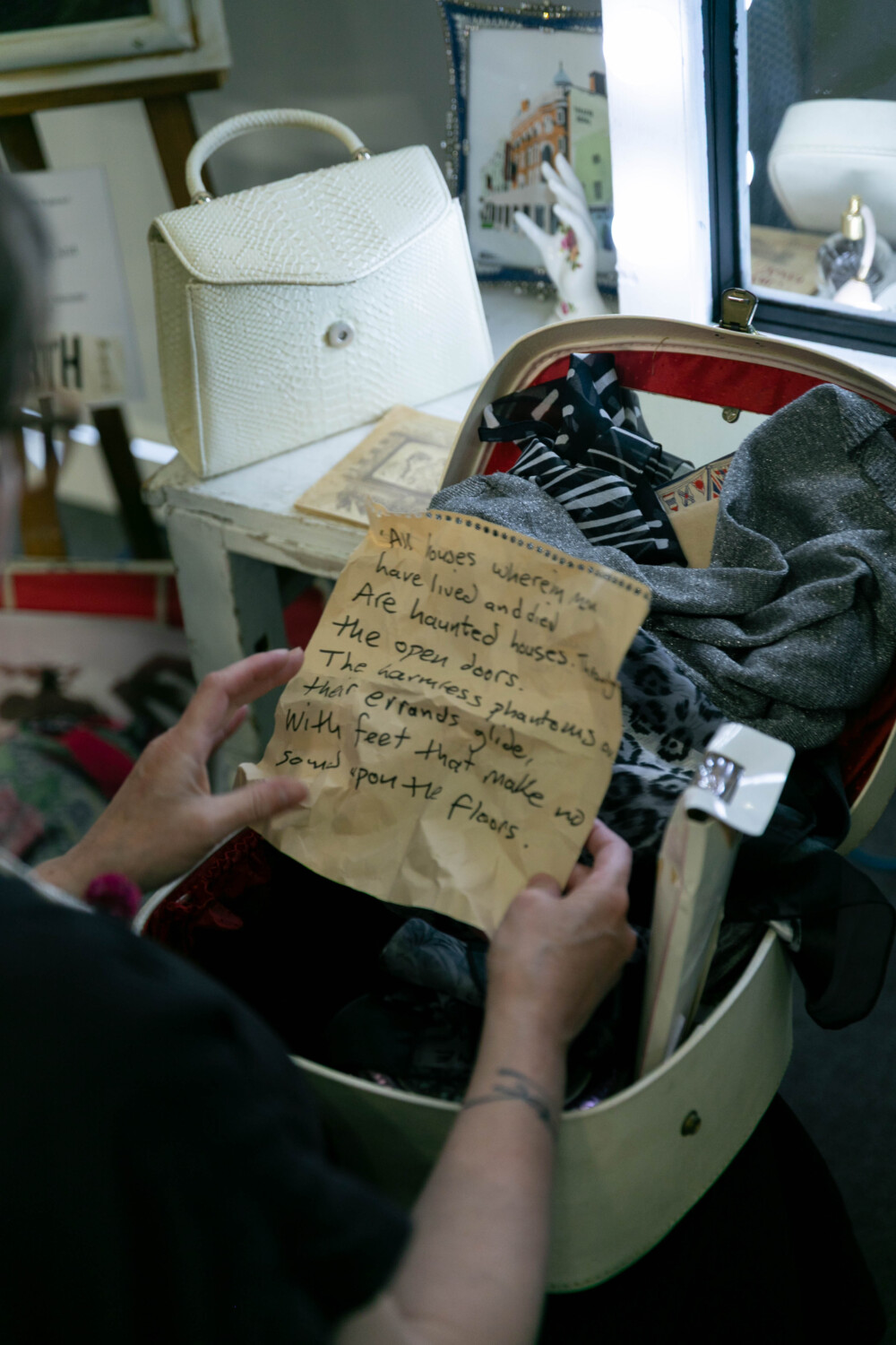 A pair of hands holds a crumpled, aged letter which they have found in an old vanity case