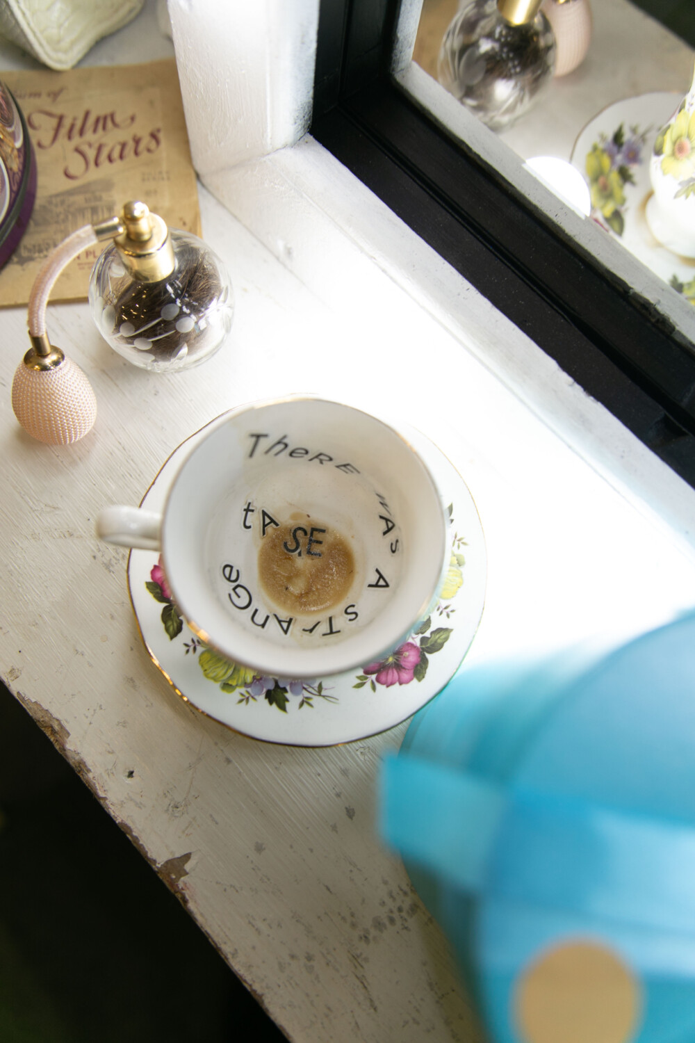 a dressing table, with an empty cup of tea. Inside the cup are some words, "There was a strange taste"