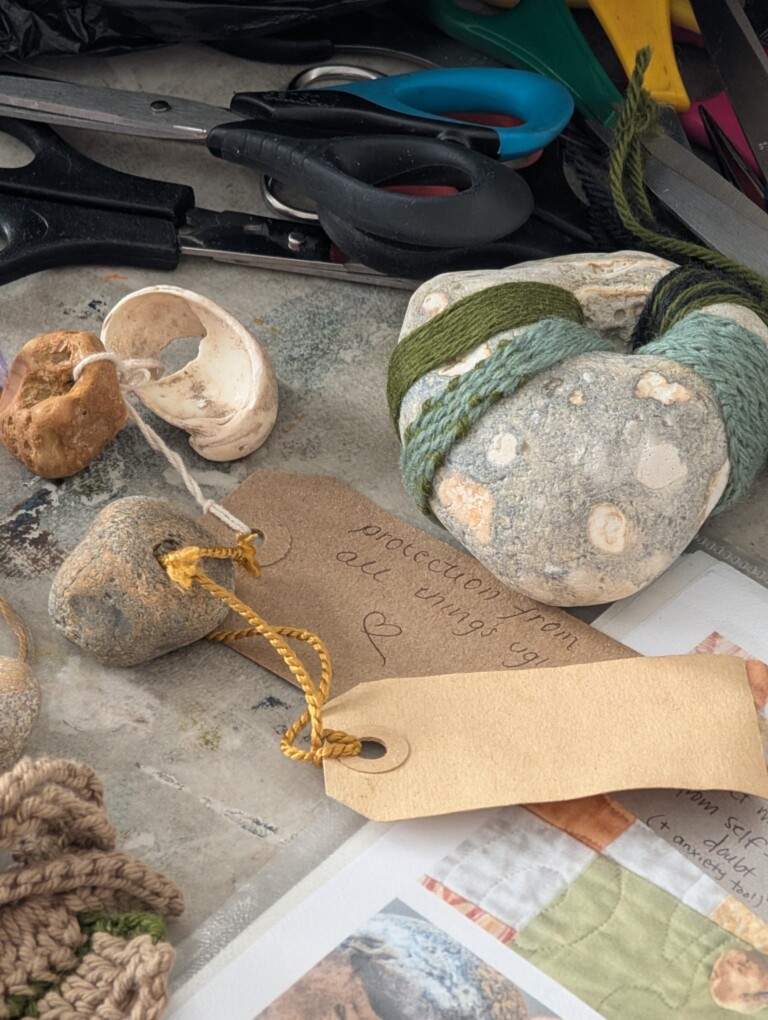 Hagstones - stones with a hole in them, are arranged on a surface with a pair of scissors, wool and labels