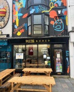 a photograph of the outside of a colourful cafe called Puzzle Bored