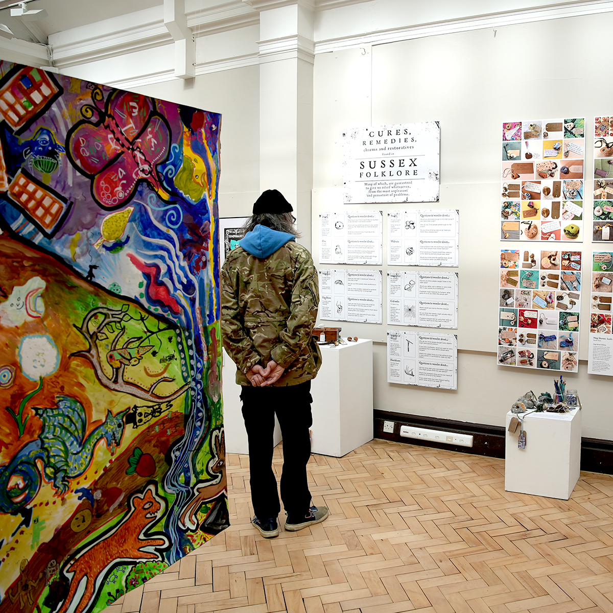 a visitor to Another Sussex art exhibition is standing looking at work in the Worthing Museum gallery