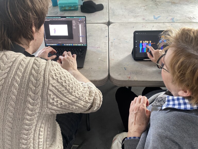 we can see the back of two people, sitting side by side, working on iPads on animation projects