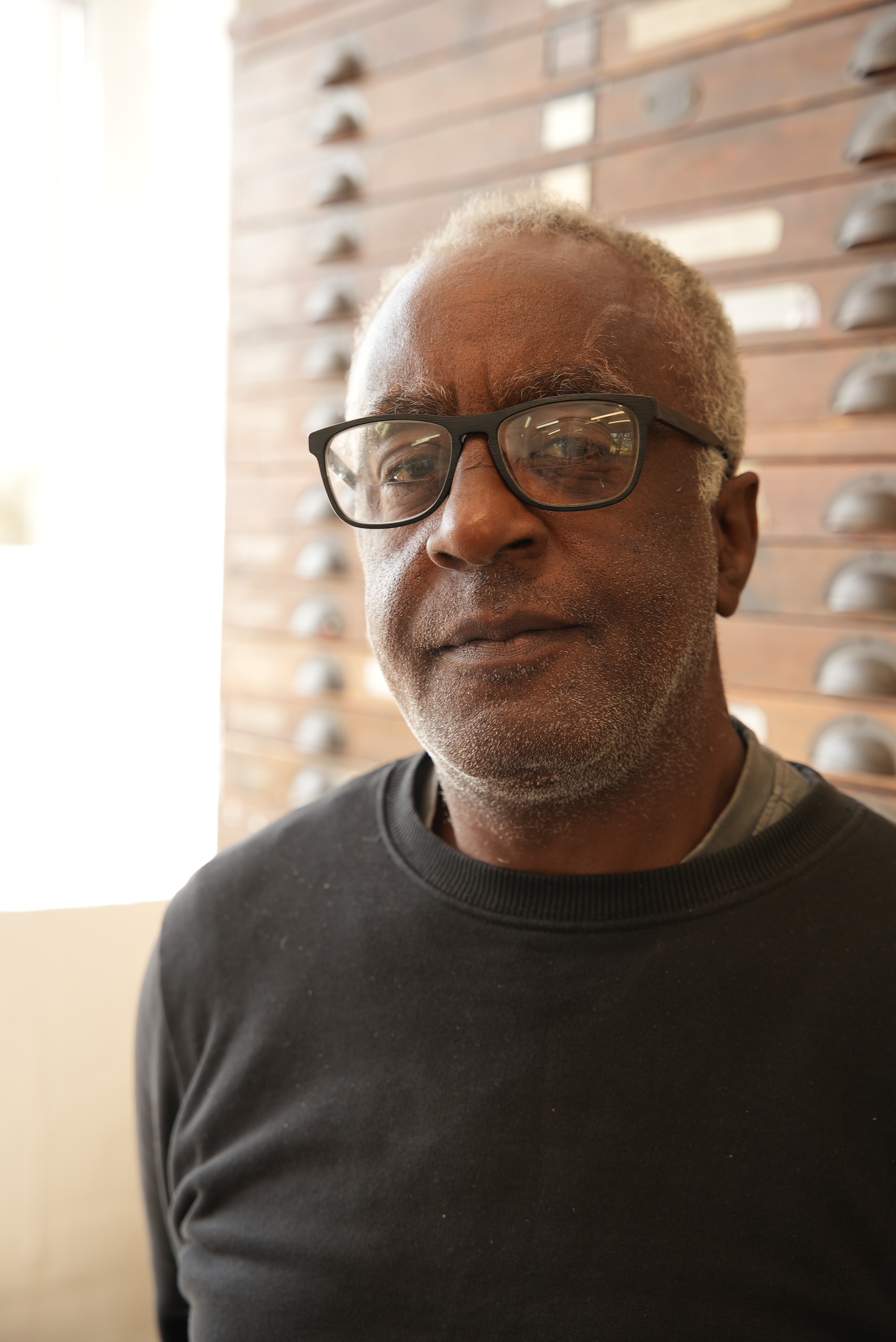 A man in glasses and a dark top is looking at the camera